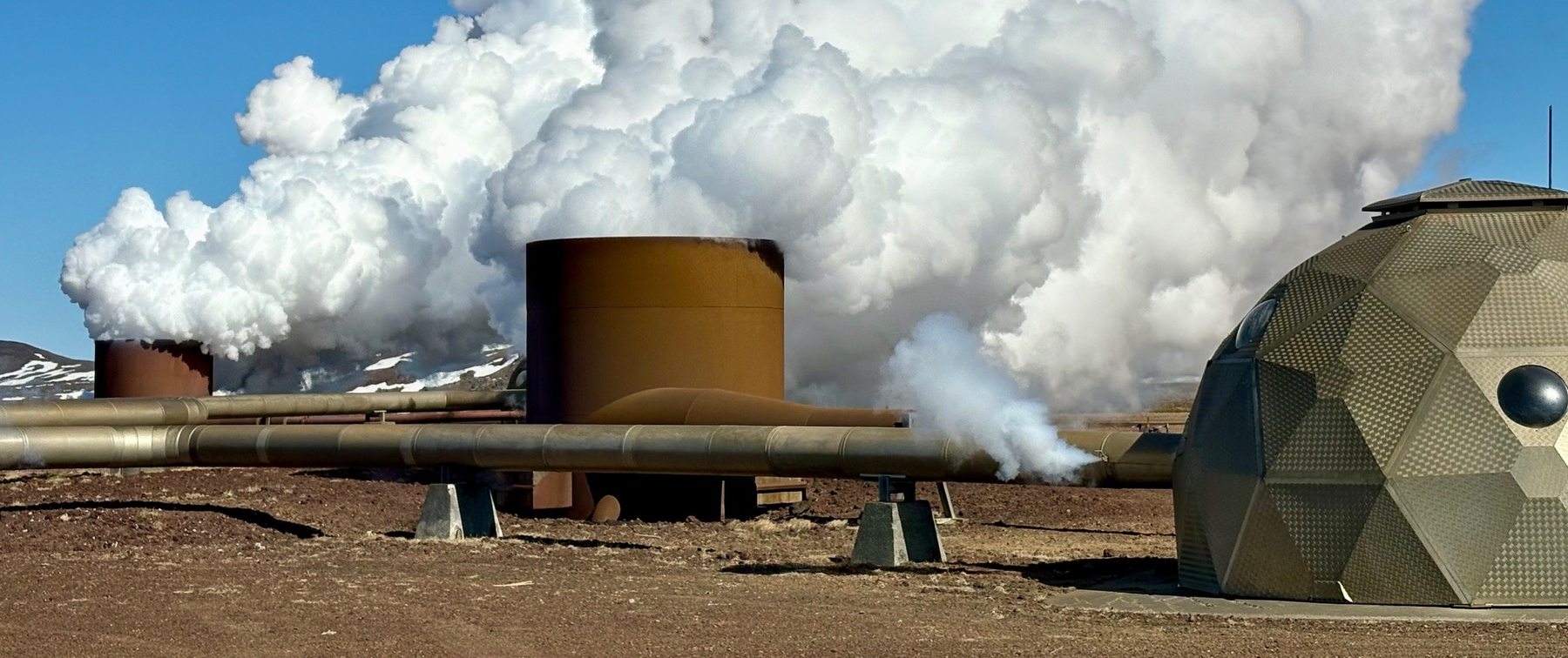 Steam rising beside pipework at a high-temperature geothermal field